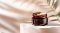 Amber glass cosmetic jar with cream on white podium against beige background with palm leaf shadow, minimal skincare product photography setup.