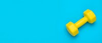 Yellow dumbbell on bright cyan background, isolated fitness equipment for gym, workout, and health design projects.