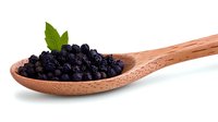 Fresh ripe blueberries in wooden spoon with green leaf on white background, healthy organic berries for natural food photography and packaging design.