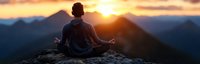 Young Asian man meditating in lotus position on mountain peak at sunset, silhouetted against golden sky and mountain ranges, practicing mindfulness outdoors.