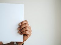 Man holding blank white card or paper against neutral background, displaying empty space for text or branding messaging.
