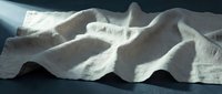 Abstract white fabric waves flowing in dramatic lighting creating sculptural forms and shadows against dark background for modern design projects.