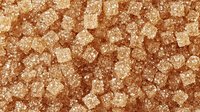 Brown sugar crystals in extreme macro photography showing natural organic crystalline structure and texture, raw unrefined sweetener background pattern.