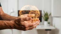 Mature man with dark skin tone holding glowing globe made of golden light particles, representing global connectivity, sustainability, and innovation for business and technology concepts.