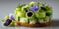 Elegant green cucumber mousse cake with edible purple flowers, microgreens and caviar pearls on crumb base for gourmet dining and culinary presentation.