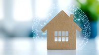 Wooden house silhouette against blurred background with digital network visualization, representing smart home technology and connected living solutions.