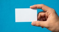 Hand holding blank white business card on bright blue background for branding and corporate identity mockup design projects.