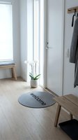 Bright Scandinavian entryway with welcome mat, white orchid, wooden bench, and coat rack, showcasing minimalist Nordic home interior design.