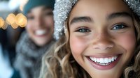 Happy children wearing knit winter hats and scarves smile outdoors during cold season. Young girl and boy enjoy festive holiday moments together in snowy weather conditions.