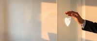 Businessman hand protecting glowing heart symbol representing care, love, healthcare insurance, employee wellbeing and corporate social responsibility concept.