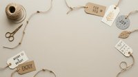 Flat lay arrangement of kraft paper gift tags with twine, scissors, and natural jute string on neutral beige background, perfect for holiday packaging and greeting card design projects.