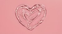 Clear transparent gel heart shape with glossy texture on pink background for skincare cosmetics and beauty product design concepts.