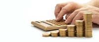 Businessman hands using calculator with golden coins stacks showing financial growth and profit calculation for investment planning and budget management.