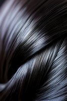 Silky smooth dark hair strands in close-up macro shot showing glossy texture and natural wave pattern, highlighting shine and healthy appearance for beauty industry.