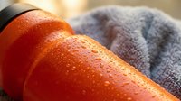 Fresh red tomatoes with water droplets on blue striped kitchen towel, ideal for food styling, cooking blogs, recipe websites, and culinary content.