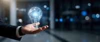 Businessman hand holding glowing globe lightbulb with digital network connections, representing innovation, technology solutions, and global business growth concepts.