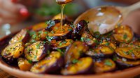 Roasted baby potatoes glazed with honey and fresh herbs on rustic wooden plate, drizzling golden syrup creates appetizing moment in warm lighting.