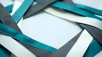 Colorful ribbons in teal, gray, and white arranged in overlapping layers on neutral background, suitable for crafts, gift wrapping, and design projects.