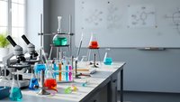 Modern chemistry laboratory with colorful glassware, microscopes and scientific equipment on white bench for research and education.
