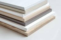 Stacked layers of various colored melamine boards and laminated panels showing thickness and texture on white background, suitable for furniture design projects.