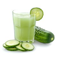 Fresh cucumber smoothie in glass with sliced cucumber garnish and whole cucumber on white background, healthy detox drink.