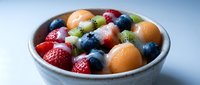 Fresh mixed fruit salad bowl with strawberries blueberries cantaloupe and kiwi for healthy breakfast dessert or snack meal preparation.
