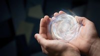 Hands holding glowing energy sphere with swirling light patterns against dark background for spiritual healing meditation and power concepts.