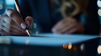 Close-up of businesswoman hands signing important contract or document with elegant pen in modern office with bokeh lights background.