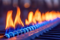 Orange flames dancing above blue gas burners in line formation create dramatic contrast against dark background, macro photography shows detailed heat pattern.