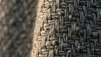 Close-up of gray knitted wool fabric texture showing detailed cable knit pattern and stitches for cozy winter clothing and textile design projects.