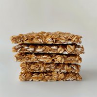 Stack of homemade granola bars with oats and honey on neutral background, healthy snack food photography for nutrition and wellness content.