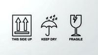 Shipping package care symbols showing this side up arrows, keep dry umbrella with raindrops, and fragile wine glass with lightning bolt on white background.