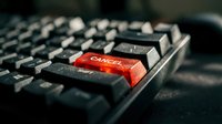Red enter key on black computer keyboard with shallow depth of field for technology and business concepts.