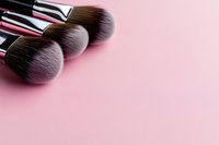 Professional makeup brushes with soft synthetic bristles arranged on pink background, close-up view with copy space for beauty and cosmetics industry.