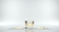 Crushed gold leaf and foil fragments scattered around a clear glass cube on reflective surface, isolated on white background for design and commercial use.