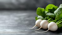 Fresh white turnips with bright green leaves on dark concrete background with copy space, selective focus. Food photography for healthy eating concept.