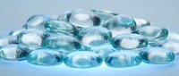 Clear blue glass marbles scattered on white surface creating elegant decorative arrangement for crafts and interior design projects.