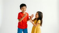 Happy Asian children playing together giving high five in red and yellow clothes on white background isolated for design use.
