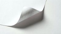 White paper sheet with curled corner creating shadow on clean background for office documents and business presentations.