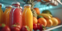 Fresh fruit juices in glass bottles with strawberries and oranges on kitchen counter for healthy breakfast and wellness lifestyle nutrition.