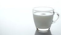 Glass mug filled with fresh white milk on clean surface with soft lighting for healthy breakfast and dairy product concepts.