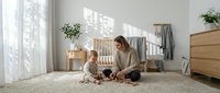 Young Caucasian mother and toddler playing with wooden toys on carpet in bright Scandinavian nursery room with natural light.