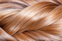 Macro view of glossy blonde braided hair texture showing interweaving strands with natural highlights and lowlights creating dimensional pattern.