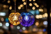 Glowing decorative spheres with intricate patterns in gold and blue colors hanging against blurred bokeh background create magical festive atmosphere.
