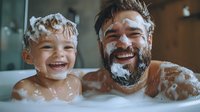 Father and young son having fun bath time together, covered in soap bubbles and foam, sharing joyful laughter in intimate family moment. Authentic parenting lifestyle.