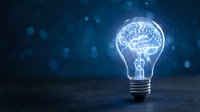 Glowing light bulb with brain inside on dark blue background with bokeh lights representing innovation, creativity, intelligence and bright ideas for business concepts.