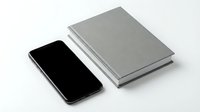 Modern smartphone with blank screen next to stack of gray notebooks on white background for business and technology concepts.