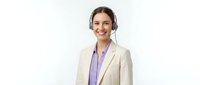 Smiling young Caucasian businesswoman with headset in beige blazer providing customer service support on white background isolated for business design.