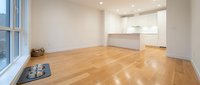 Empty modern apartment with hardwood flooring, white walls, and minimalist kitchen. Suitable for real estate listings, interior design portfolios, and home decor marketing.