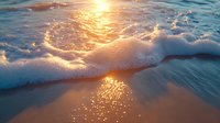 Gentle ocean waves washing onto sandy beach at sunset with golden sunlight reflecting off water surface creating magical sparkles and foam patterns.